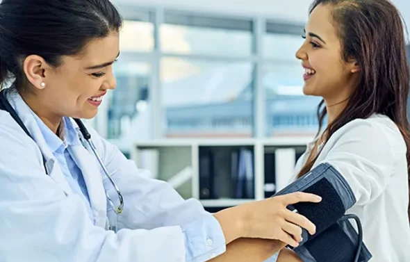 A fellow measures blood pressure for a patient with hyperten