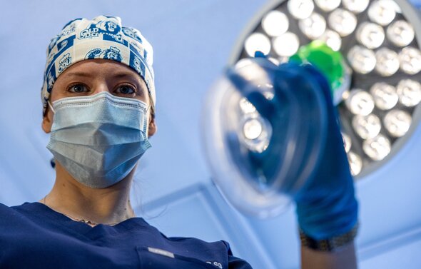 Nurse holds oxygen mask in operating room.