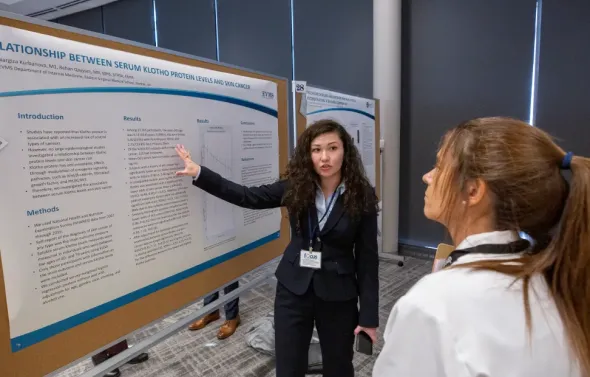 A female presenter is explaining a project poster to another