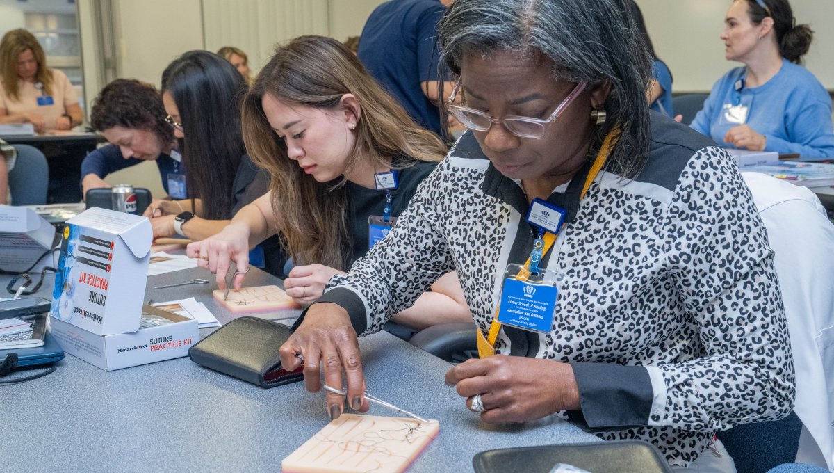 Nursing students practice with sutures in classroom setting.