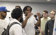 Black student demonstrating something with his hands to onlookers