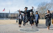 A student jumps in the air while walking across the ODU seal.