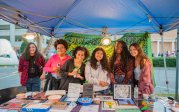 A group of female students pose for a photo behind a table at an event. 