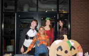 A group of people in Halloween costumes pose for a photo.