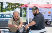 Two men look at a boat engine