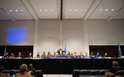 A group of people sit at a table at a conference.