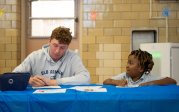 An ODU student sits at a table drawing with a elementary school student.