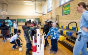 A group of elementary school students play games together in a gym.