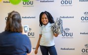 An elementary school student poses with a pom pom in front of an ODU backdrop.