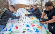 In addition to handprints, students write messages of condolences and support for Lt. Col. Brandon Shah (B.S. ’07) onto Dominion Rock as they return from Spring Break.