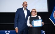 Liza Flores holds award while posing for picture with ODU President Brian O. Hemphill.