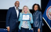 Christine Nickel holds award while posing for picture with ODU President Brian O. Hemphill.