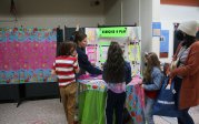 A group of children gathered around a table displaying a colorful poster, engaged in discussion and observation.