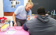 A woman checks a patient's blood pressure using a blood pressure cuff.