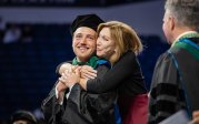 A mom holds her son during the doctor of medicine ceremony.
