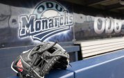 A baseball glove rests on a dugout wall in front of a sign that reads "ODU Monarchs."