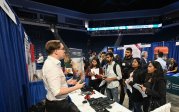 An employer talks to a group of students at an information table.