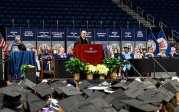 Photo of a man speaking at a podium to a crowd of people.