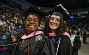 Two students smile during ODU's commencement.
