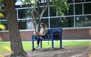 A student reads a book on a bench on ODU's campus.
