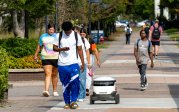 Students walk on ODU's campus alongside a delivery robot.
