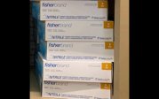 Five boxes of fisherbrand lab gloves sitting on a shelf. 