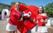 Two people pose with a heart mascot.