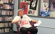 man sits in a chair holding a microphone