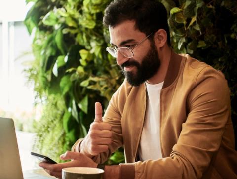 Man working on laptop giving thumbs up
