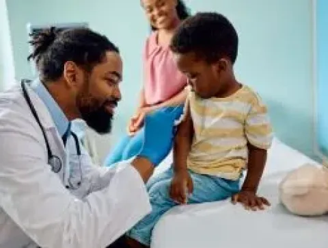 Masked pediatrician with masked mom and baby on lap
