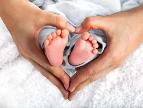 Hands forming a heart around two baby feet