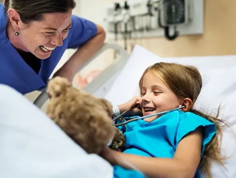 A fellow and patient laugh as the patient uses a stethoscope