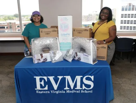 Two female staff members stand next to a display table