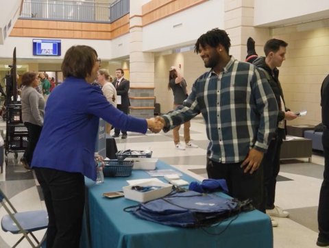 Accountancy professor greets student in School of Business lobby.