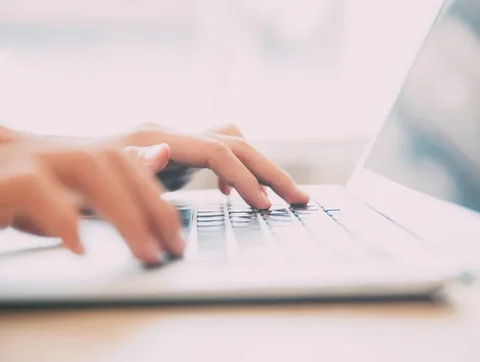 Hands typing on laptop