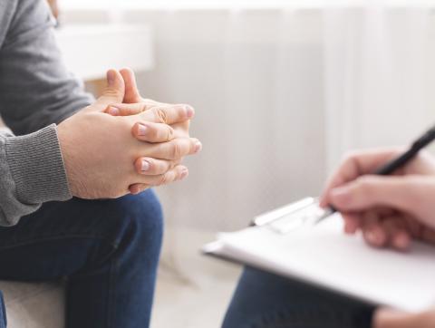 Therapist writing notes during counseling session with singl