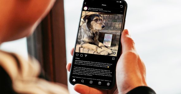A person holds a phone with an image of a dog displayed. 