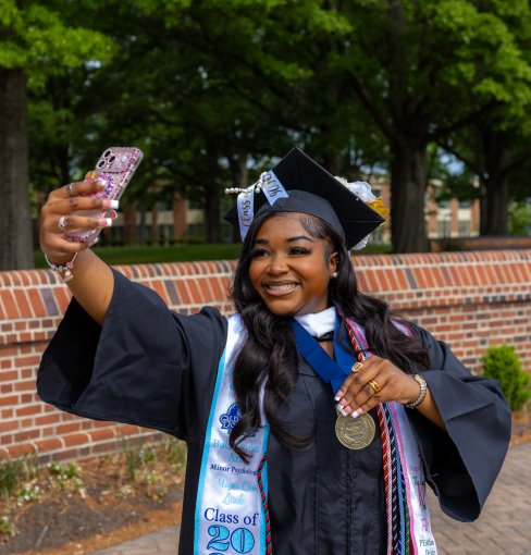 Yasmin Edwards, 2026 ODU Honors College graduate, takes a selfie while wearing a cap and gown.