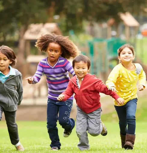 Several children run together in the park.