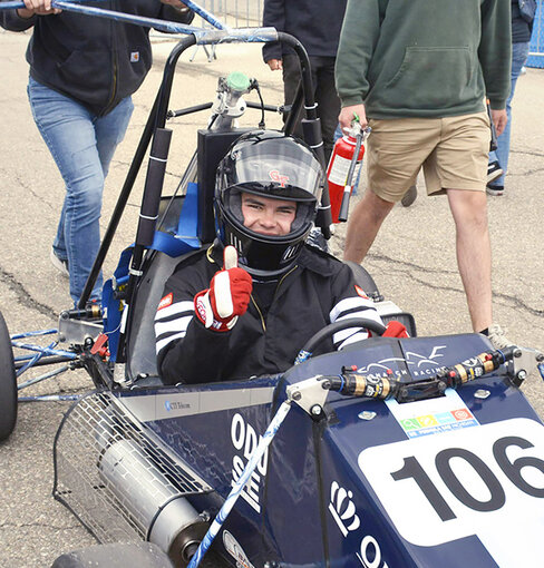 students in and near a formula car