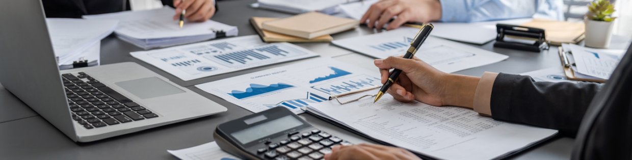 Auditor and accountant review business documents on office table.