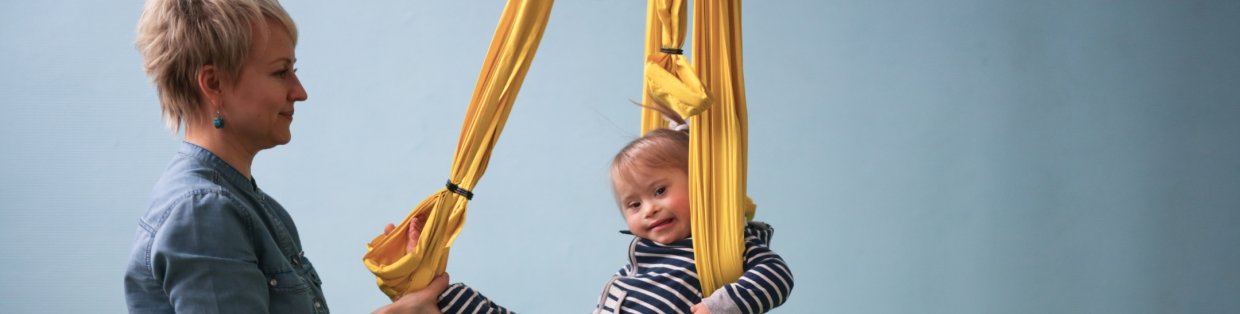 A child in an aerial sling with an adult guiding movement. 
