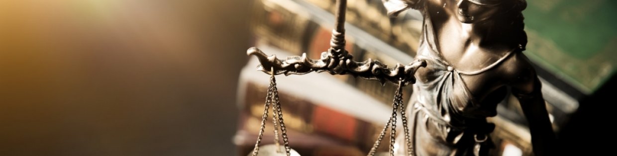 Justice scale with book in the background.