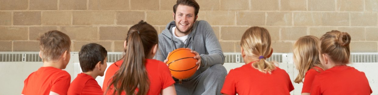 A basketball coach speaking to his team in a circle. 