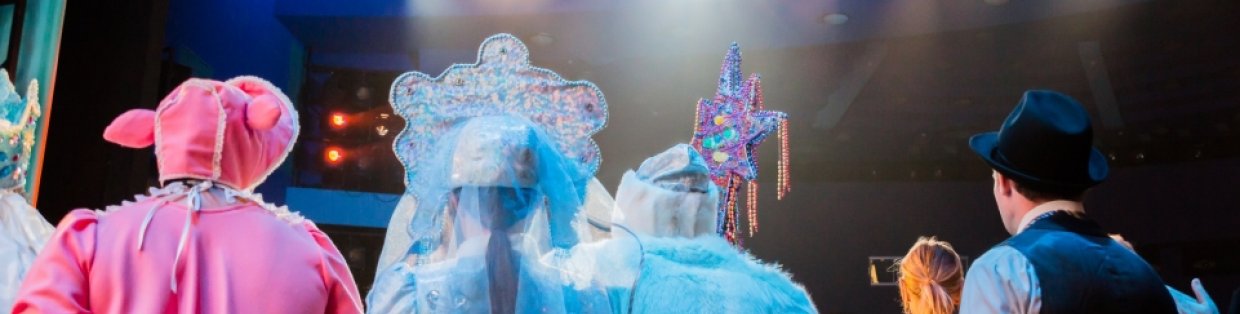 Theatre kids dressed in costume on stage looking out to the audience.