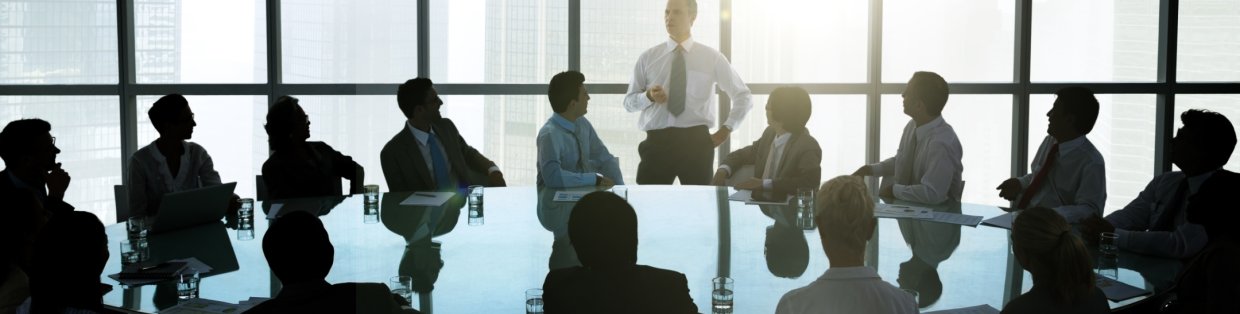 A man speaking to a conference room filled with professionals. 