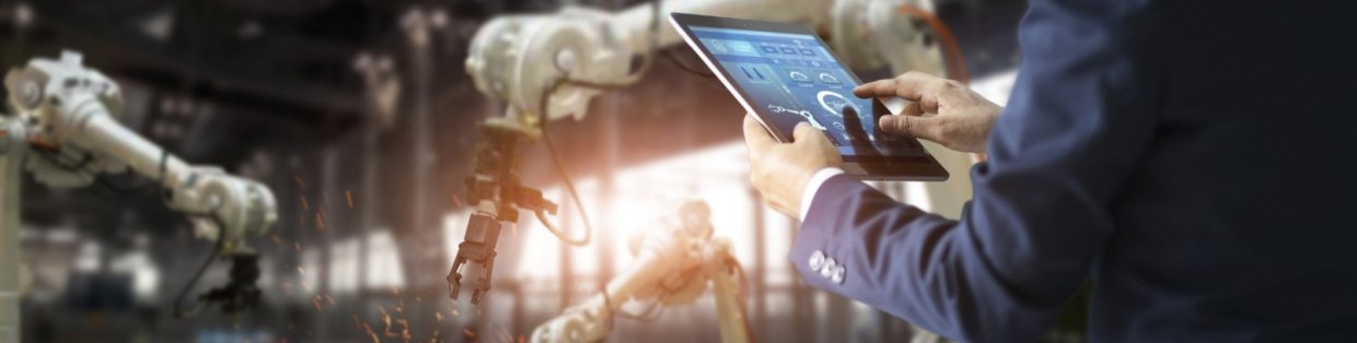 A person holding an ipad looking over an industrial space. 