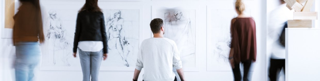 People gazing at art on a wall in a studio.