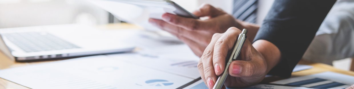 business management header image with people looking over clipboards with charts.