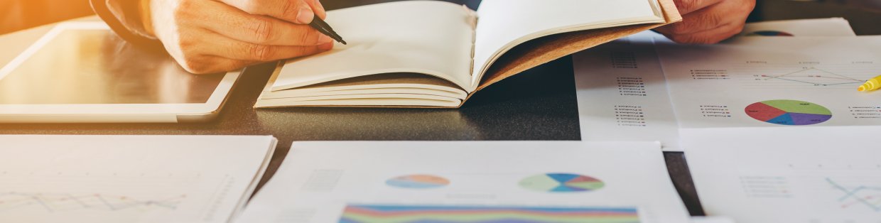 businessman looking through a notebook with a pen in hand. 